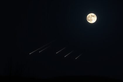 A high-resolution image of a dark sky with a bright full moon and multiple meteors streaking across the horizon, with a few trees or hills in the foreground to give a sense of depth and perspective.
