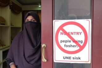 A photo of a person wearing a hijab or burqa being denied entry to a jewellery shop in Bihar, with a sign on the door stating "No entry to people wearing hijab, burqa, mask"
